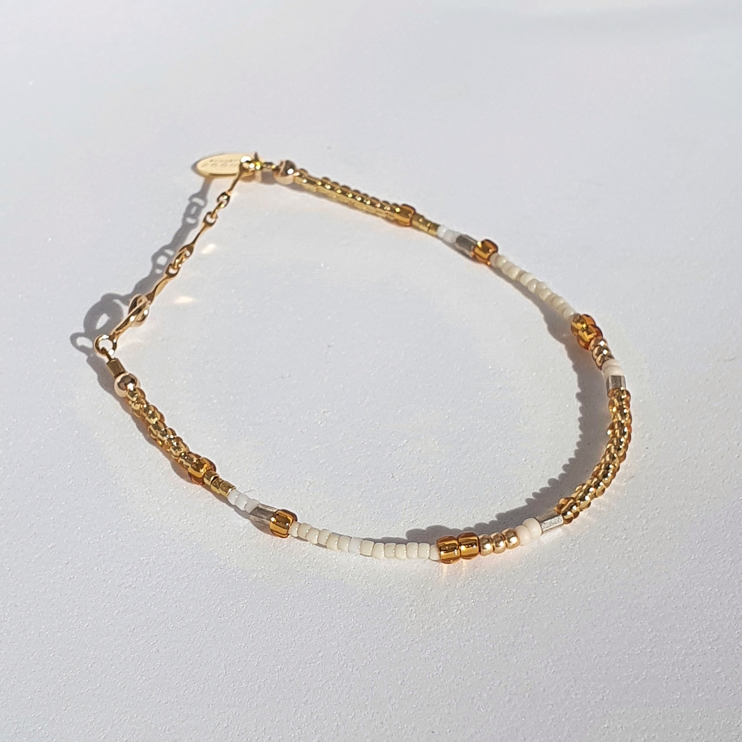 A minimal, tonal design featuring gold and white coloured glass seed beads.